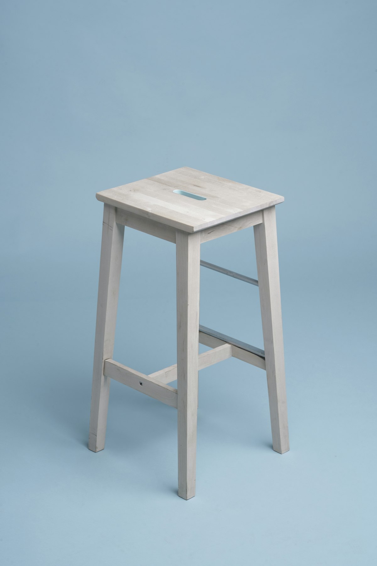 Tabouret haut en bois clair sur fond bleu
